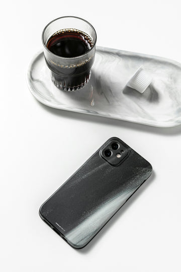 a cup of coffee and a cell phone on a tray